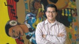 hispanic latinx man posing in front of a mural depicting musical notes and people playing instruments