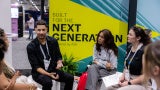 one man four women against a banner backdrop that says "built for the next generation" expo floor