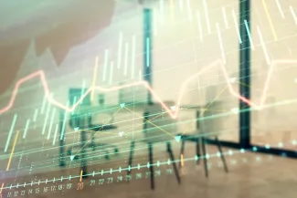 Multiple colorful graphs on a pane of glass with a conference table and chair in the background