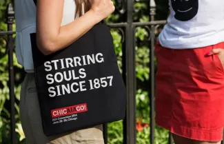 Person holding a tote bag that reads "Stirring Souls Since 1857"