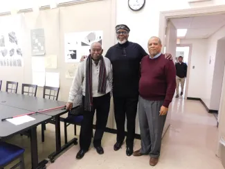 Three men posing for a photo in a conference room