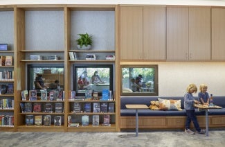 Children sitting at table next to library stacks of Atherton Library.