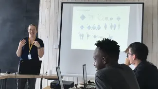 An instructor and three young people with computers in a meeting space