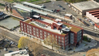 Aerial view of brick residential building next to train tracks