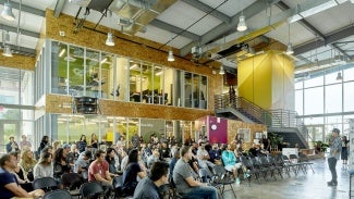 A person is talking to a large group inside the The Entrepreneurs Sandbox