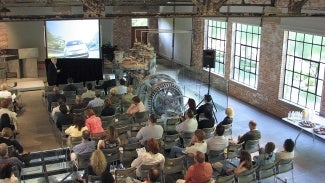 People attend a theater-style lecture in a converted factory building