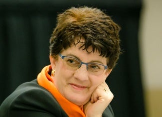 headshot of woman with short hair and glasses resting her chin on her hand