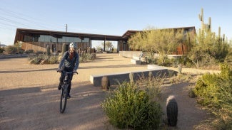 Person biking outside of Pima Dynamite Trailhead on a sunny day