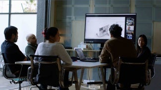 a group gathered in a conference room looking at designs on a large monitor