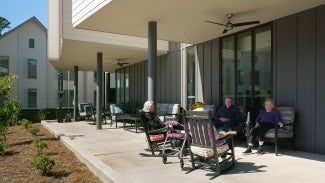 Two residents relax on a patio outside the building.  