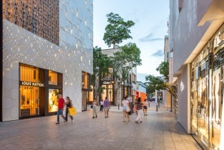 Pedestrians walk past a Louis Vitton store in a shopping district.