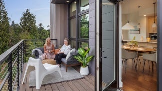 Residents sit together on outdoor patio, open door leads to kitchen area.