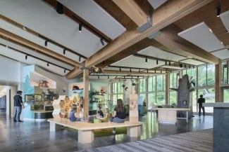 The main public exhibit space opens up with views to the north woods and south prairie, connecting interpretive content with the surrounding landscape.