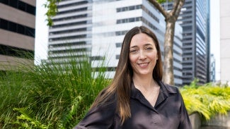 Headshot of a woman with long dark hair in a dark blouse standing outside 