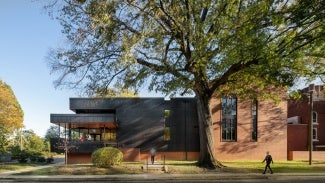 External view of a brick community center from the street. There is a large tree in the foreground.