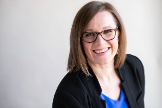 Headshot of a woman with short brown hair wearing glasses and a dark jacket 