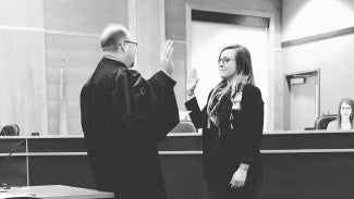 Black and white image of a woman being sworn in by a judge.