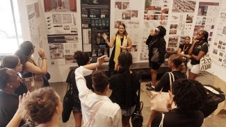 A woman giving a presentation to a group of people in front of a display.