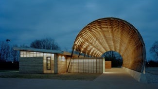 Building exterior at dusk. The building has a large curved canopy. 