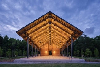 Exterior view of a wooden pavilion at night. 