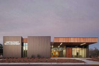Front elevation of a community health building at dusk. 