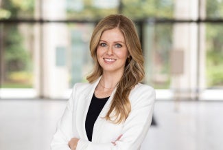 Headshot of a woman with long blonde hair wearing a white jacket. 