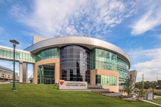 Rear view of a medical building at day. The building sits on a hill and the rear facade is curved. 