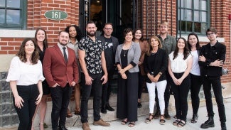 A group of people post outside a brick building.