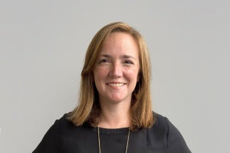 Headshot of a woman with long red hair in a dark blouse