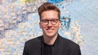 Headshot of a man wearing glasses and a dark blazer 