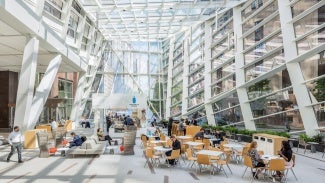 Interior view of a glass atrium with tables and chairs. 