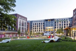 a large grassy square with sculptural elements in a mixed use development.