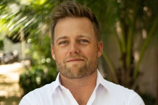 Head shot of a man with short blonde hair wearing a light shirt