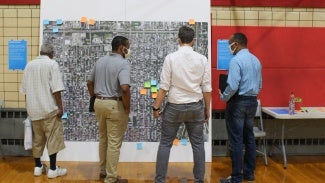 Four people stand in front of a neighborhood map