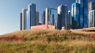 A city skyline with a grassy hill in the foreground.
