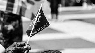 A hand holding the Juneteenth flag