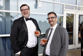 two men in suits holding red beverages AIA26 opening night party hilton bayfront