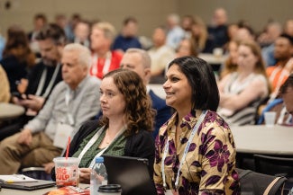 two women attendees in crowded room at a conference session