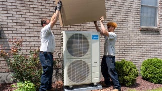 Two people working on an HVAC system