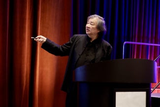 shigeru ban japanese architect giving presentation against colorful curtain background