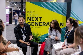 one man four women against a banner backdrop that says "built for the next generation" expo floor