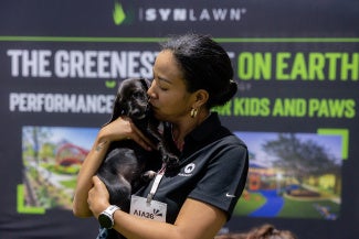 woman kissing a black lab puppy on expo floor
