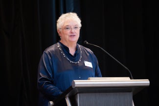 carole wedge faia aia evp ceo standing behind podium against black background