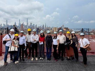 group of architecture students in hard hats in front of new york city skyline