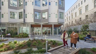 two women walking in front of apartment complex with landscaping and common space