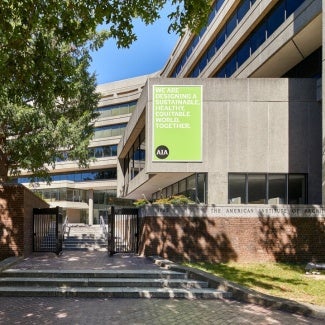 building exterior with a sign that reads we are designing a sustainable, healthy, equitable world, together - AIA