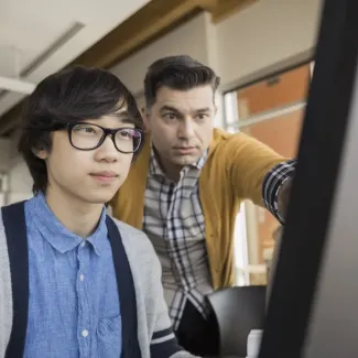 Student and teacher looking at computer