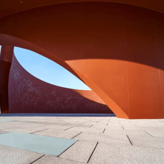 Architectural concept rendering of an reddish orange metal curved building
