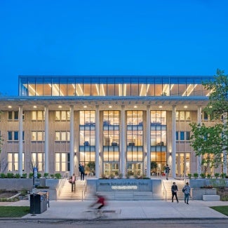 building with columns and a glass facade lit up from inside