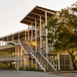 Modern 3 story building at sunset, with stairs on the exterior leading up to the second floor
